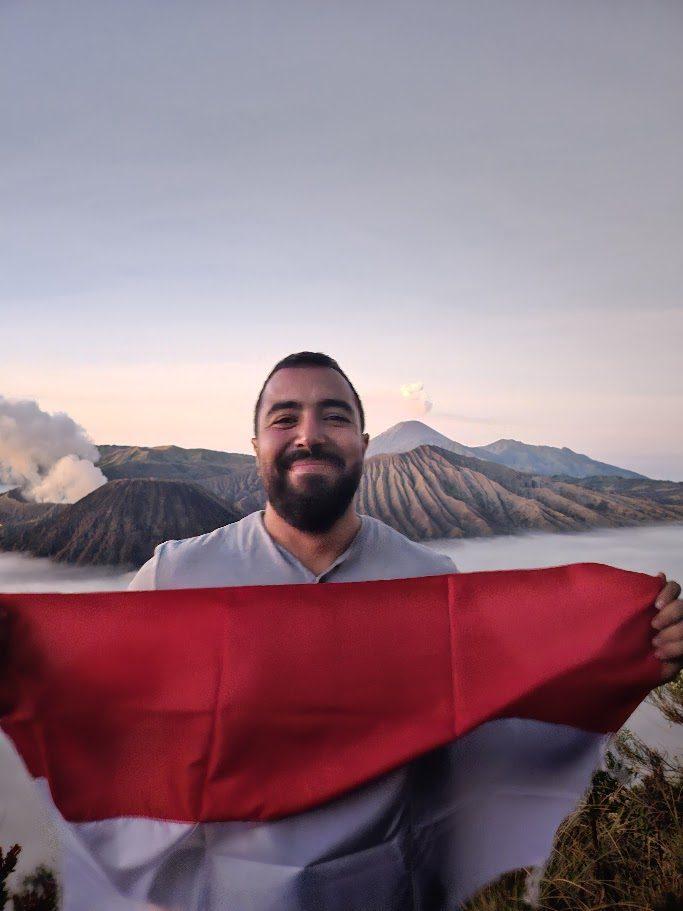 Younes tenant un drapeau indonésien devant les volcans du Bromo, Java, Indonésie